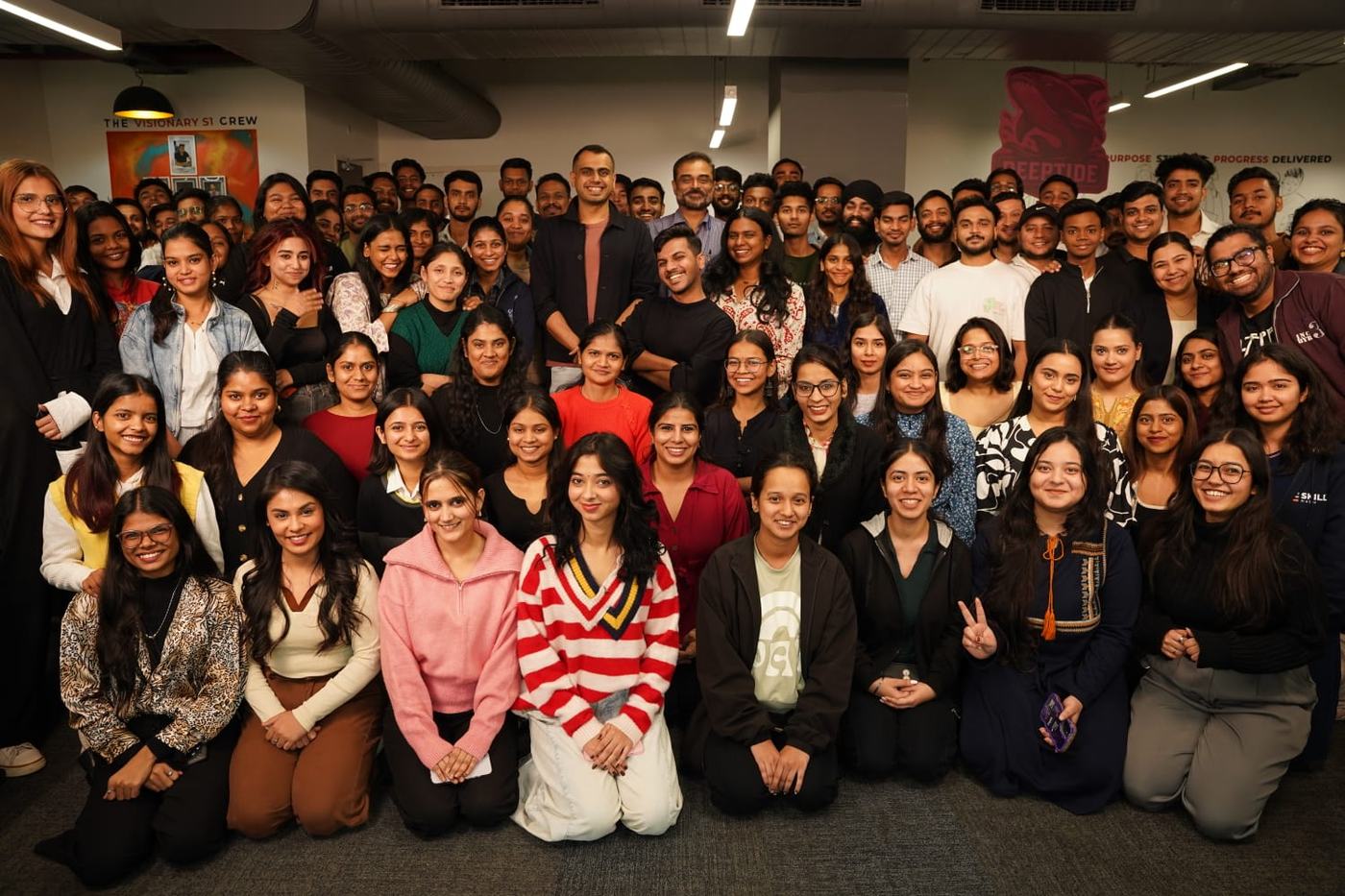Around a hundred members of the Skillinabox team together in the office, most of them women, smiling at the camera.